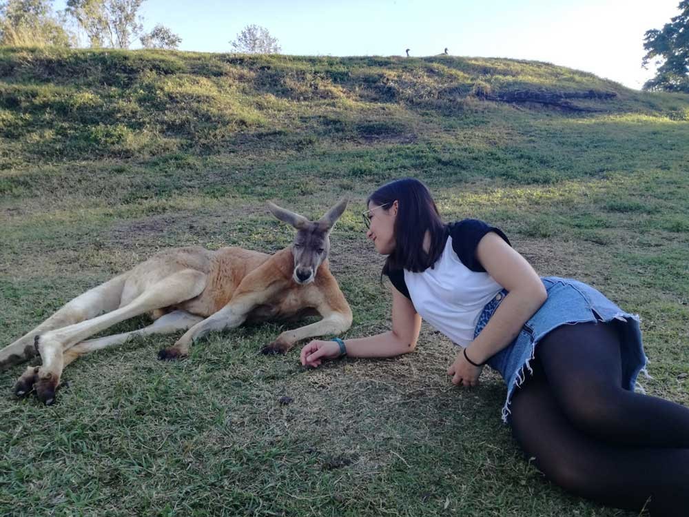 chica morena estirada en el césped y delante un canguro